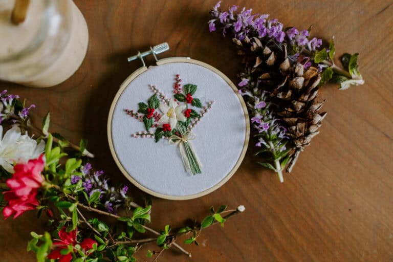 Birth flower embroidery hoop surrounded by cut flowers and coffee.